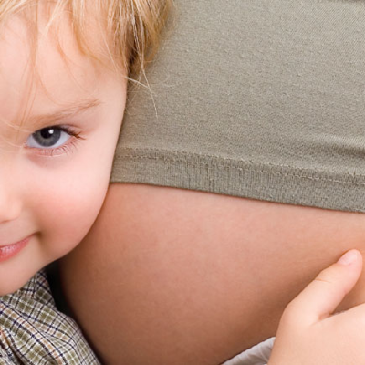 A child is hugging the belly of a pregnant woman